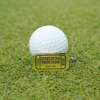 Birdie Show Ball Marker on the green in front of a golf ball, highlighting its compact design and premium finish.