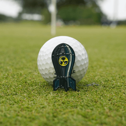 Bombs Away Ball Marker on the green in front of a golf ball, highlighting its compact design and premium finish.
